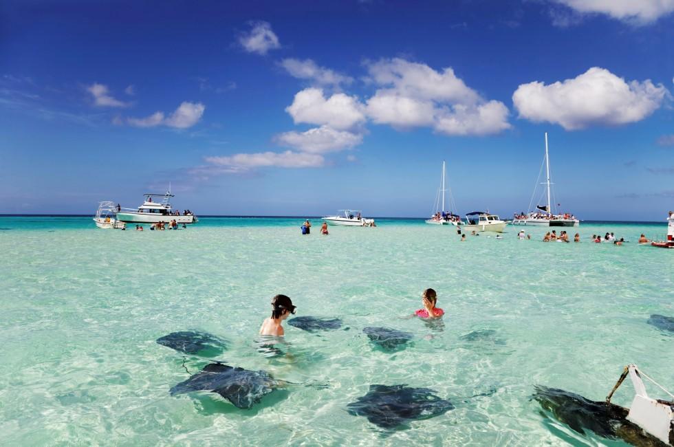 Brother &amp; sister enjoy playing with the stingrays at the sandbar off Grand Cayman. 