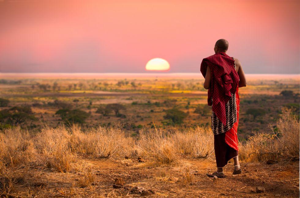 Massai man, wearing traditional blankets, overlooks Serengetti in Tanzania