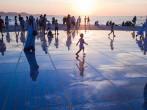 People watch sunset over Adriatic sea on large circular urban installation Greeting to the Sun at sunset time in Zadar Croatia.